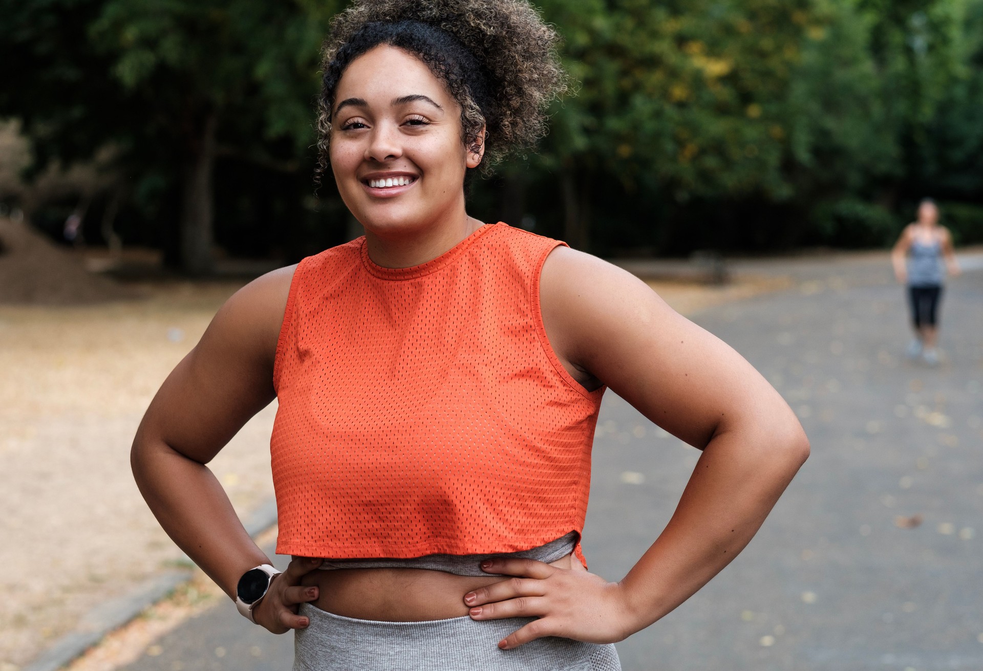 Portrait of smiling young woman standing on a road park and looking at camera.